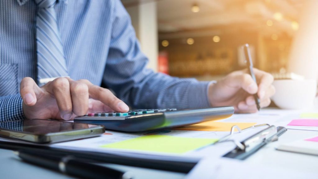 Business professional calculating financial data and reviewing documents at a desk