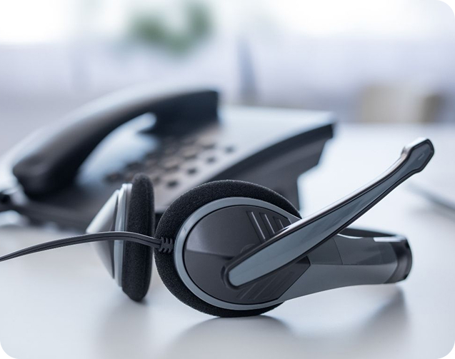 VoIP headset placed next to a desk phone in a modern office communication setup