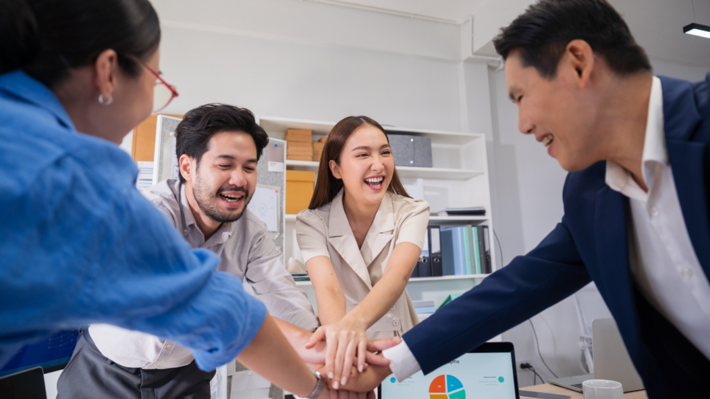 Business team placing hands together to show teamwork and collaboration in an office